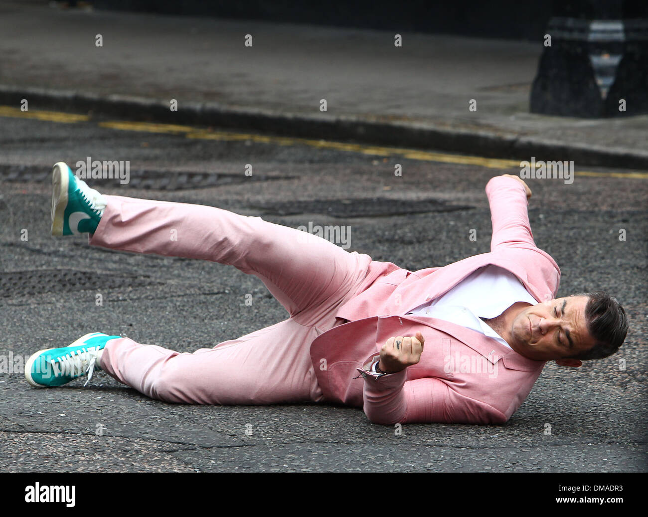 Robbie Williams performs a breakdance routine in a pink suit and turquoise  Nike high-top shoes as he films scenes for his new Stock Photo - Alamy