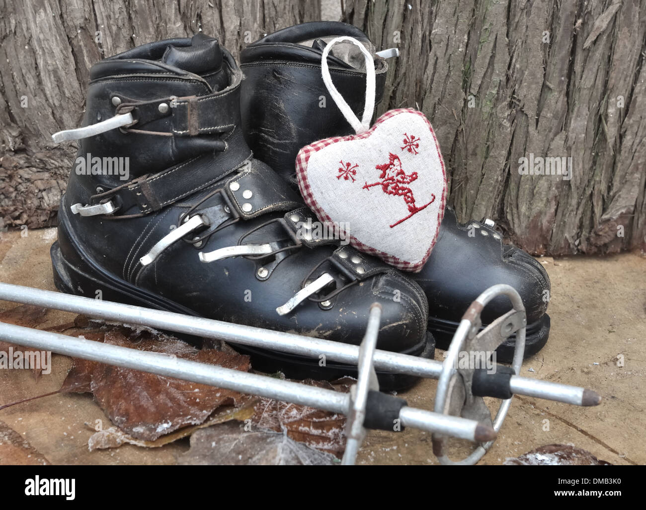 old ski boots in a rustic setting with a heart shaped cushion Stock Photo
