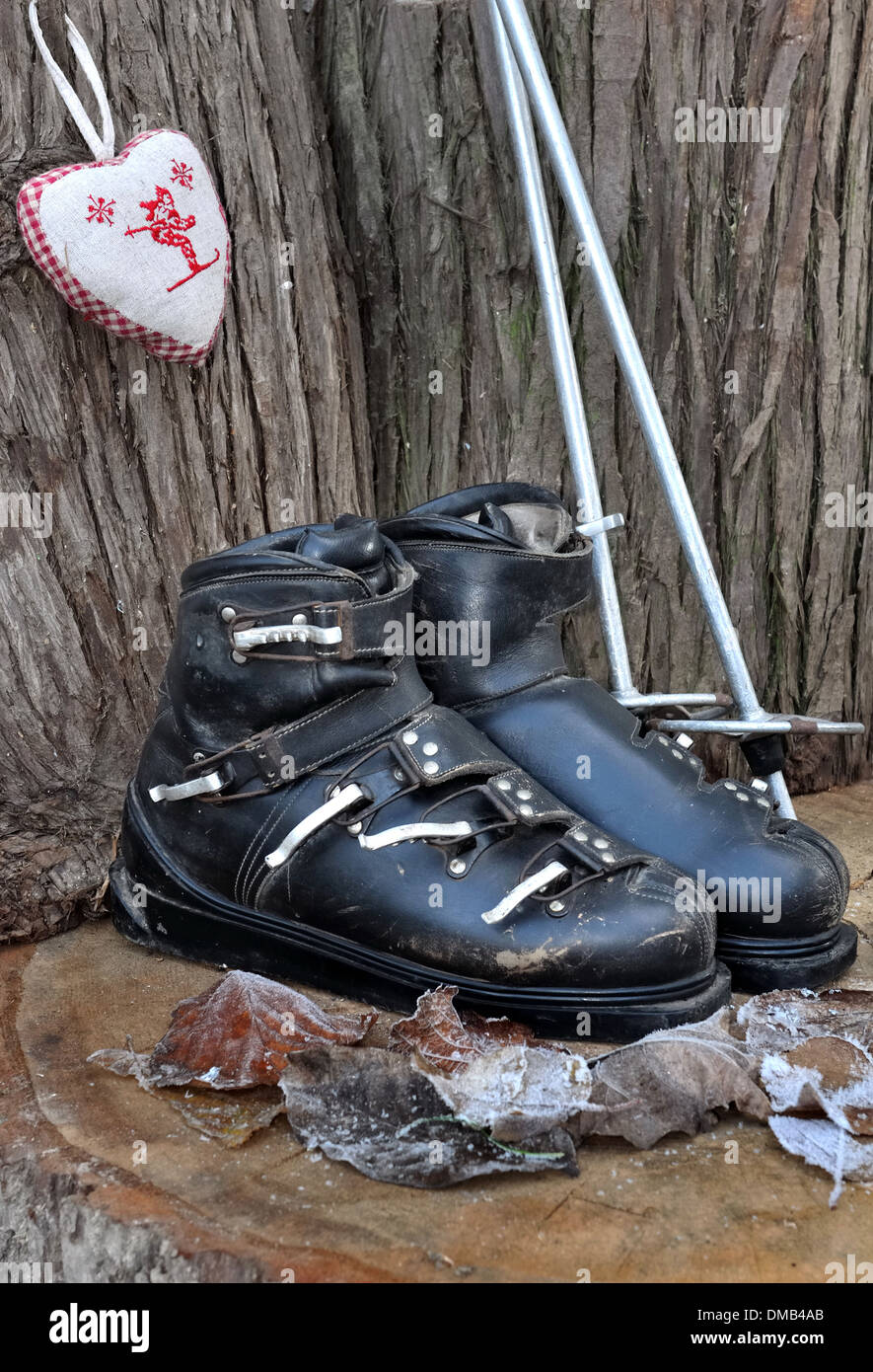 old ski boots in a rustic setting with a heart shaped cushion Stock Photo
