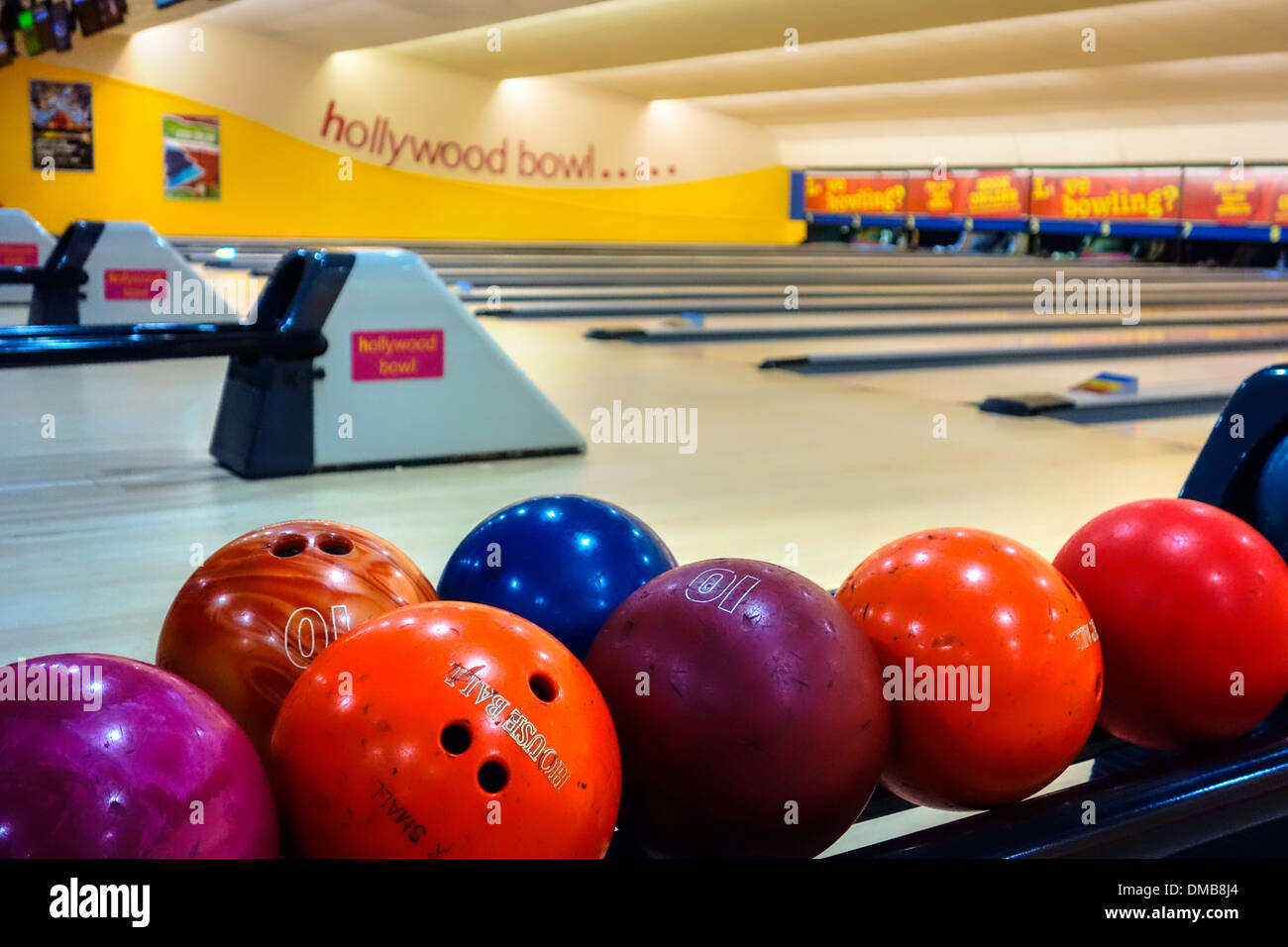 Colourful bowling balls lined up on rack ready for play. Stock Photo