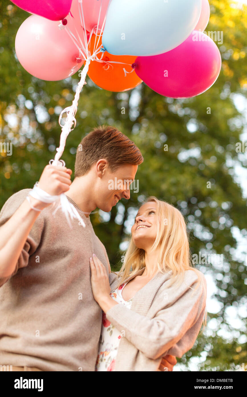 smiling couple with colorful balloons in park Stock Photo