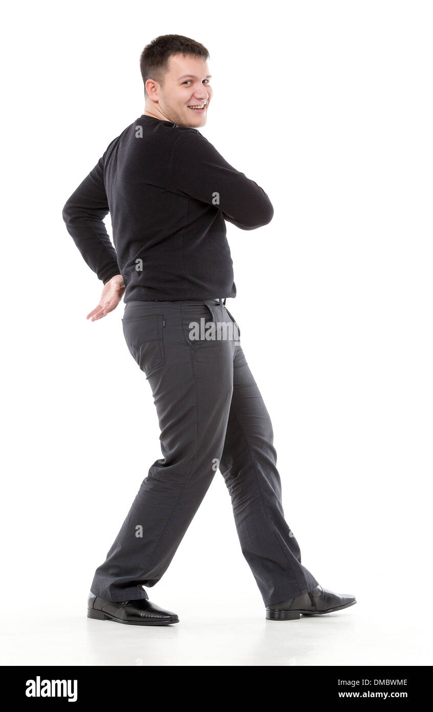 Smiling confident overweight man walking along swinging his arms or dancing and looking at the camera with a friendly smile Stock Photo