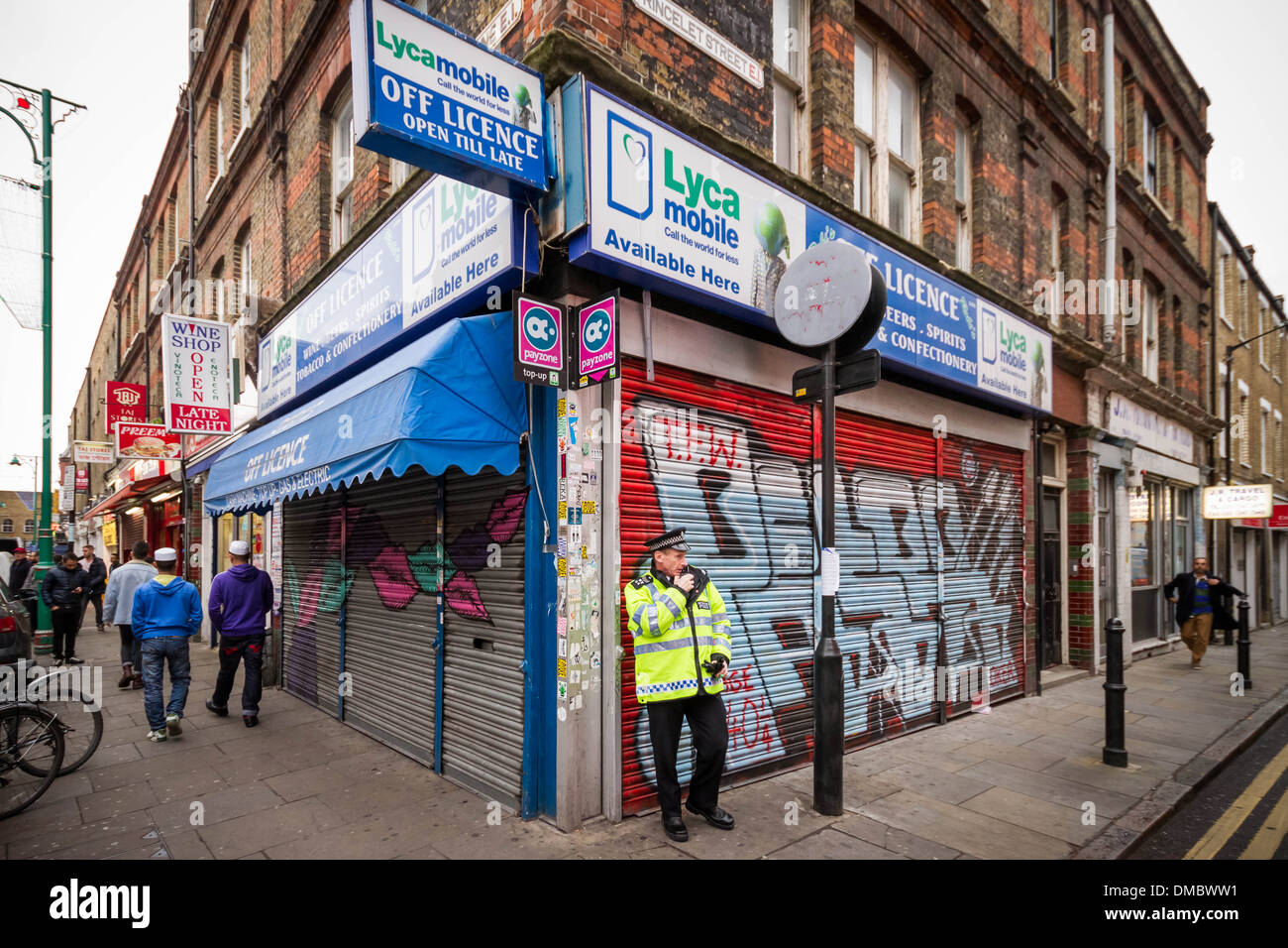 A Police officer stands guard outside one of the many Off Licence stores in London's Brick Lane. Stock Photo