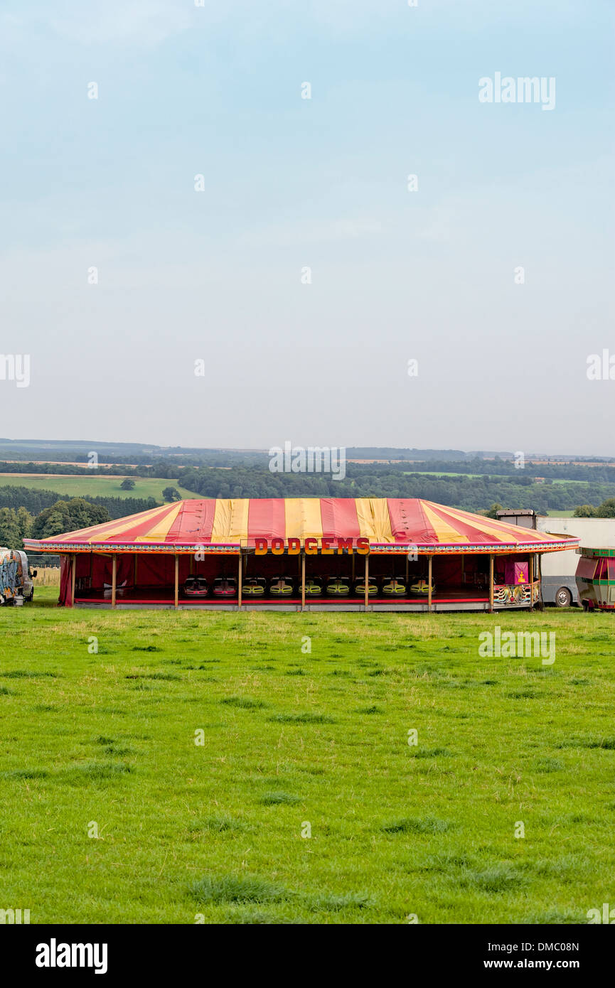 Parked dodgems in a colorful colourful red and yellow tent in a field at a British music festival. Stock Photo
