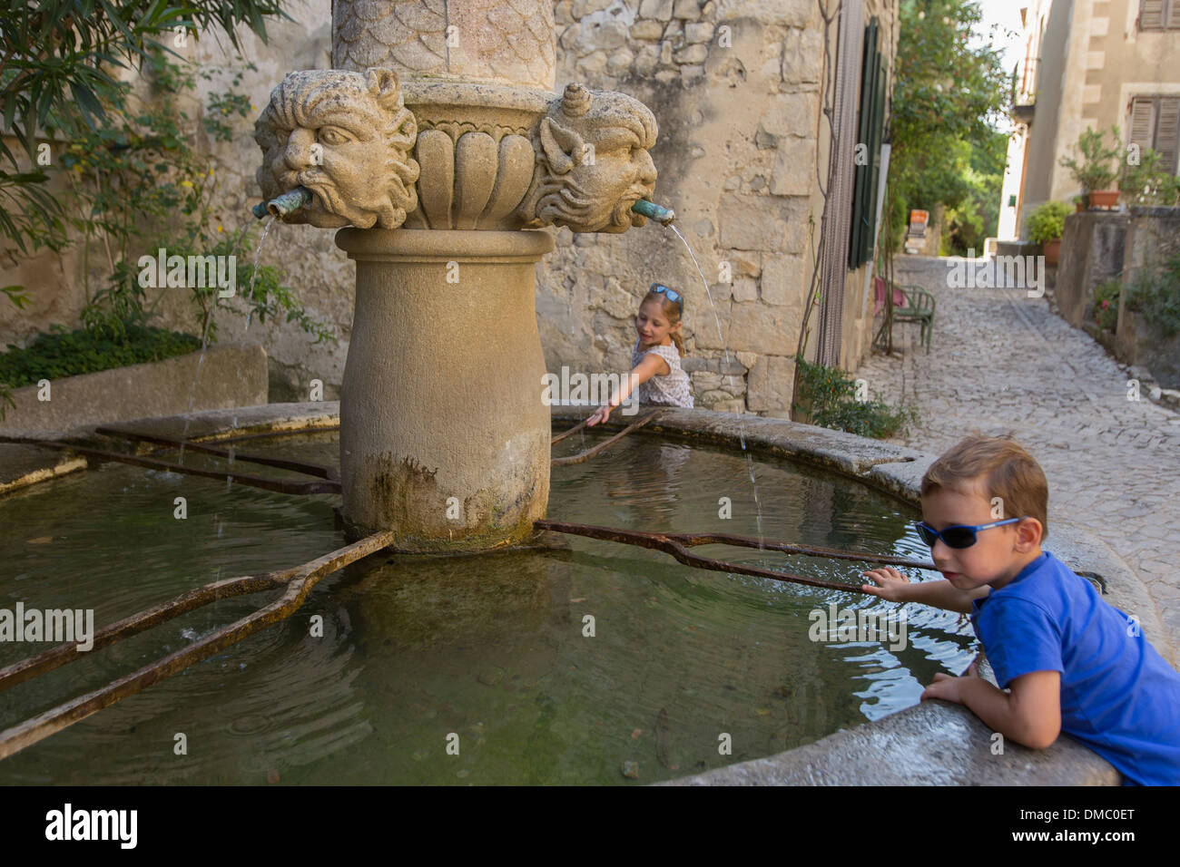 CHILD PLAYING ON THE EDGE OF A FOUNTAIN WITH GARGOYLES, VILLAGE OF SEGURET, LABELLED ONE OF THE MOST BEAUTIFUL VILLAGES OF FRANCE, VAUCLUSE (84), FRANCE Stock Photo