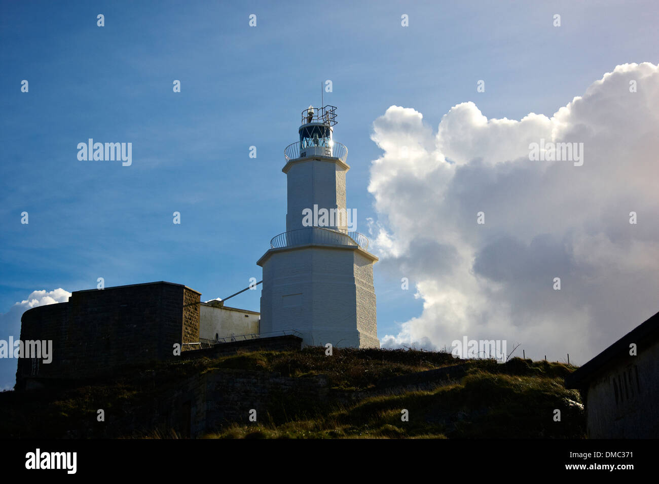 Low angle view of Mumbles lighthouse on bright sunny November day with some World War Two buildings to either side Stock Photo