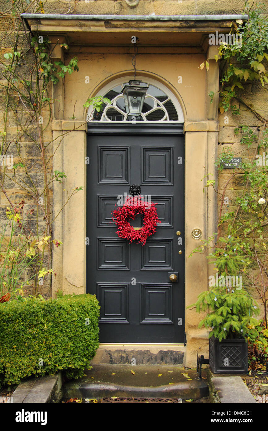 Christmas wreath hanging on front door o  traditional English country home, Ashford-in-the-Water,  Peak District, Derbyshire Stock Photo