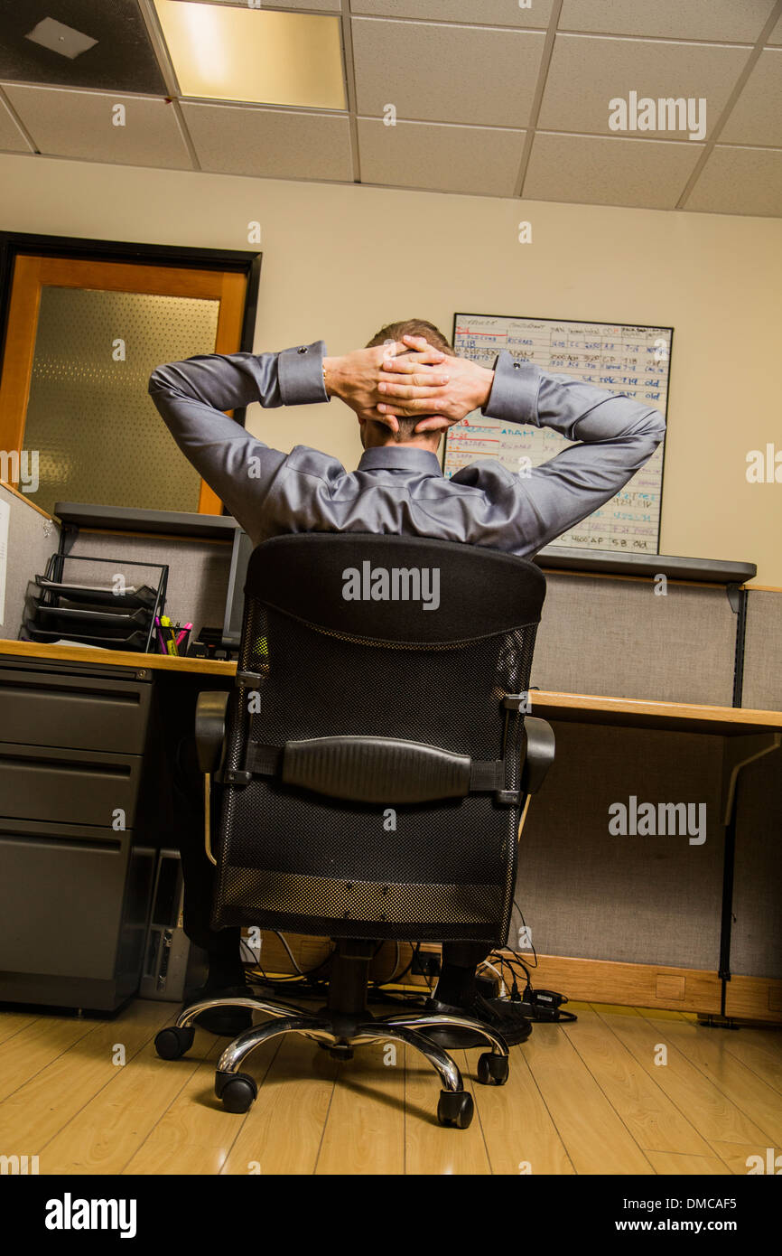 Man in office chair with hands behind head Stock Photo