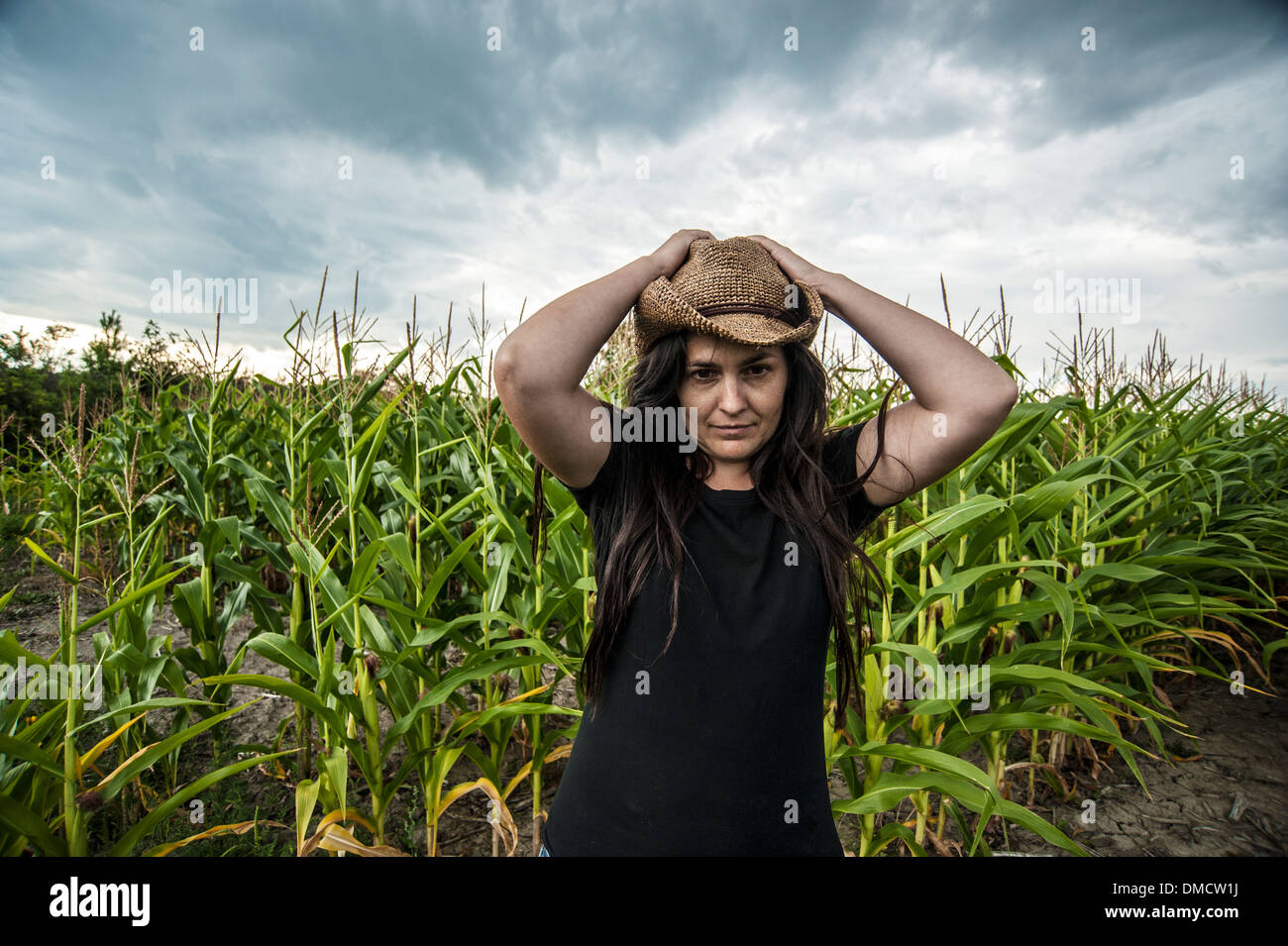 Woman standing in corn field wearing straw hat under stormy sky Stock ...