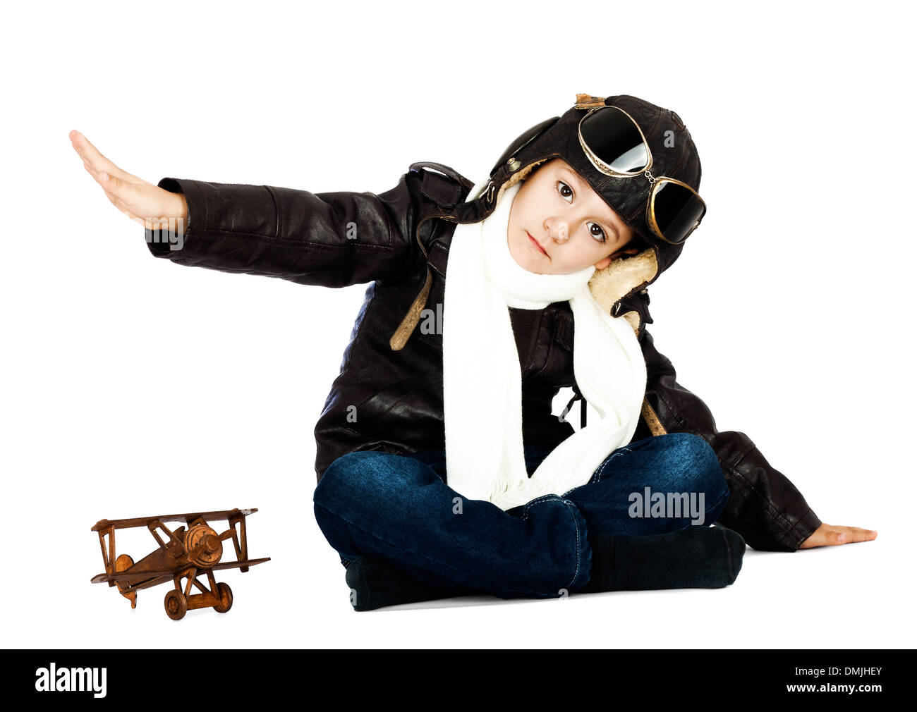 Happy cute boy dressed like a World War II pilot playing with wooden airplane toy on white background.Vintage look Stock Photo