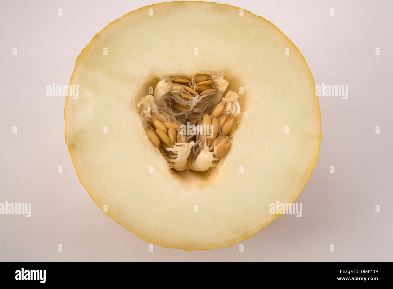 Close up half honey dew melon with seeds in centre on white background