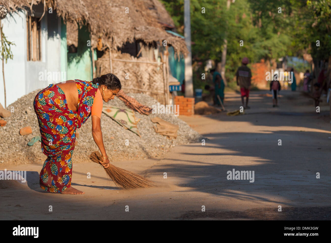 OLD INDIAN WOMAN DRESSED IN A TRADITIONAL SARI SWEEPING IN FRONT OF HER HOUSE IN A VILLAGE IN THE FARMING REGION OF CHETTINAD, STATE OF TAMIL NADU, IINDIA Stock Photo