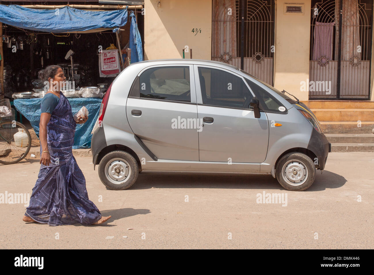 INDIAN WOMAN DRESSED IN A TRADITIONAL SARI PASSING IN FRONT OF A TATA NANO CAR, CONTRAST BETWEEN TRADITIONS AND MODERNITY, MADURAI, STATE OF TAMIL NADU, IINDIA Stock Photo