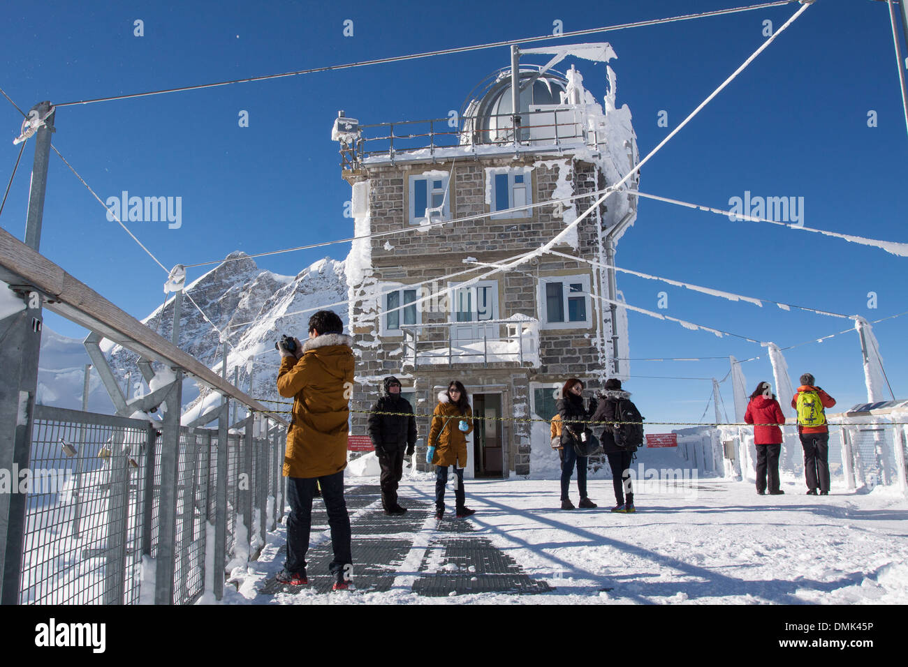 TOURISTS LOOKING AT THE LANDSCAPE FROM THE OBSERVATORY NICKNAMED THE SPHINX AT THE SUMMIT OF THE JUNGFRAUJOCH PASS, BERNESE ALPS, CANTON OF BERN, SWITZERLAND Stock Photo