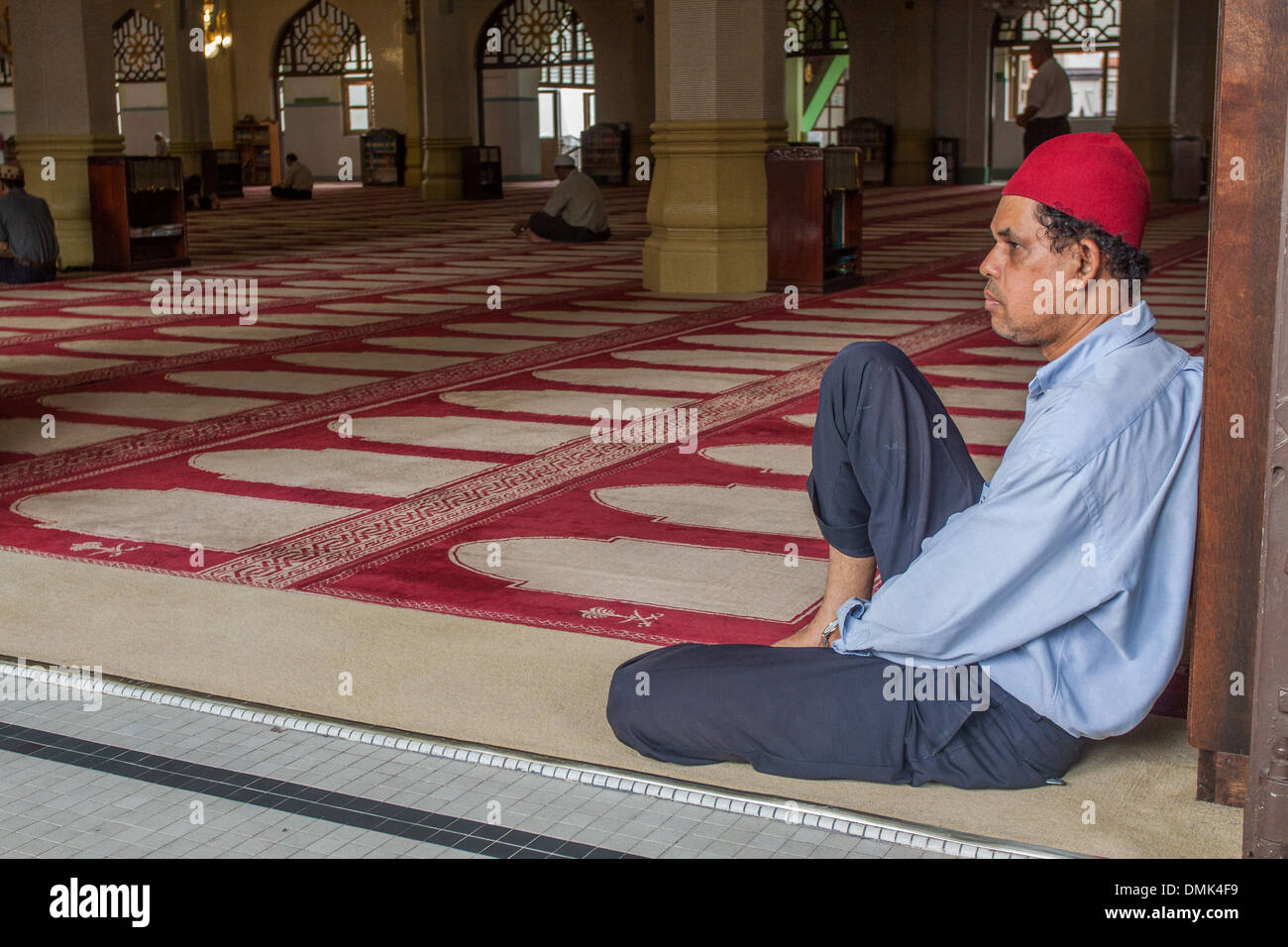 MUSLIM MEDITATING NEAR THE PRAYER RUGS OF THE MASJID SULTAN MOSQUE, THE MAIN MOSQUE FOR THE MALAYSIAN AND INDONESIAN COMMUNITY OF SINGAPORE, NEIGHBORHOOD OF KAMPONG GLAM, SINGAPORE Stock Photo