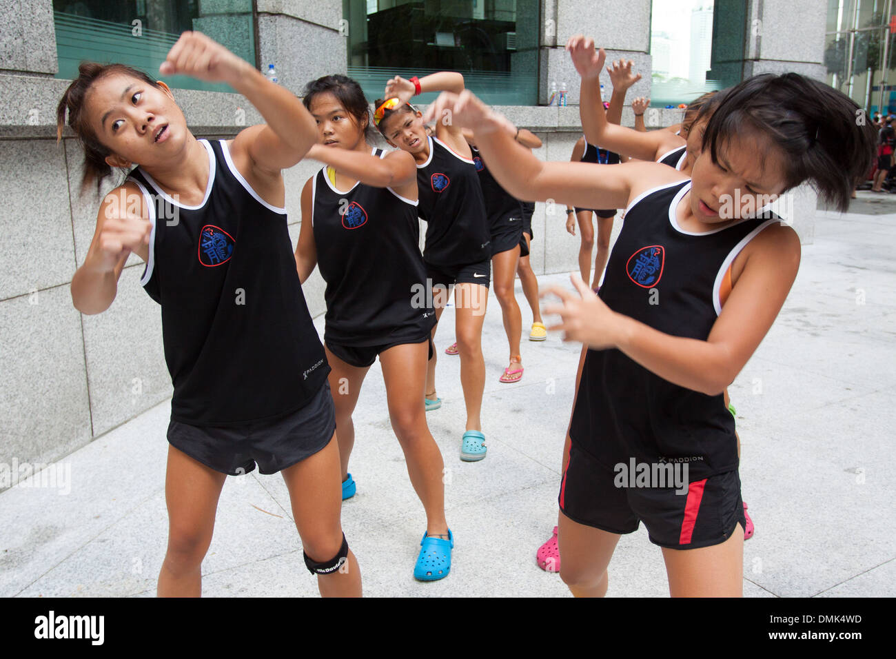 YOUNG WOMEN TRAINING FOR A RACE ABOARD DRAGON BOATS, CENTRAL BUSINESS DISTRICT, SINGAPORE Stock Photo