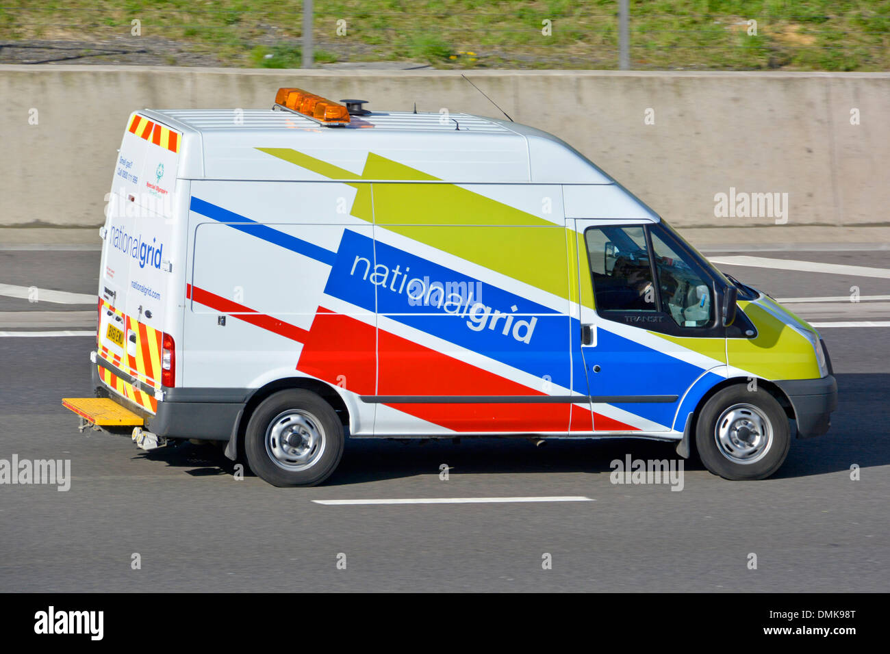 Side view Ford Transit van driver in commercial vehicle operated by the National Grid driving along m25 motorway road Essex England UK Stock Photo
