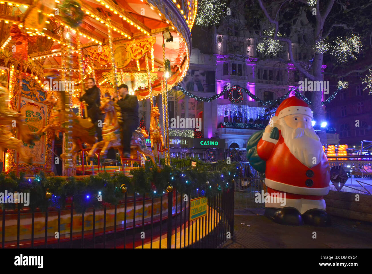Leicester Square Christmas fairground at night large plastic Father Christmas beside carousel merry go round roundabout West End London England UK Stock Photo