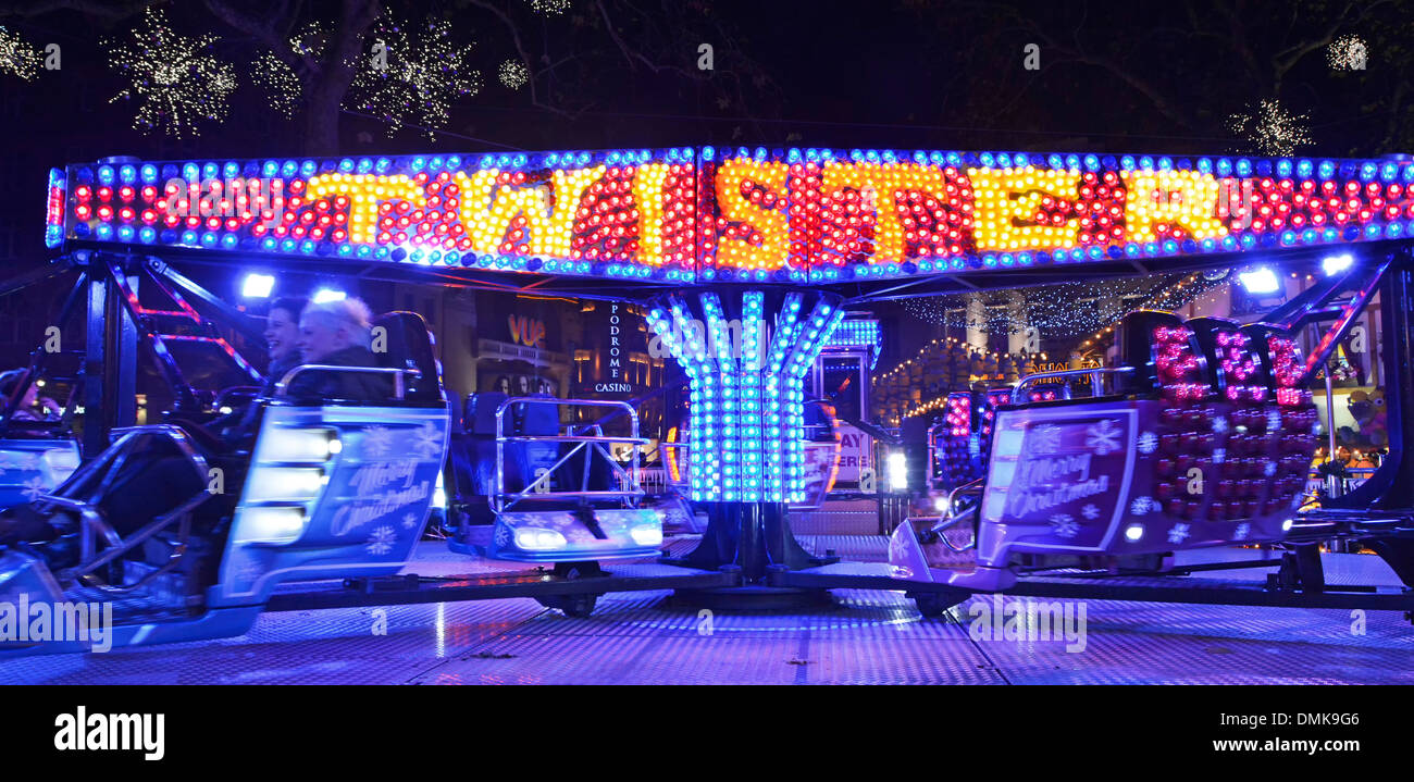 Leicester Square Christmas fairground at night with people on Twister ...