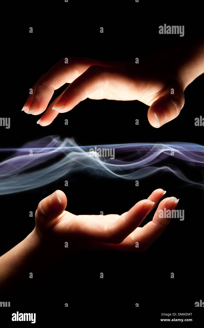 Hands almost touching light beams or smoke trails Stock Photo