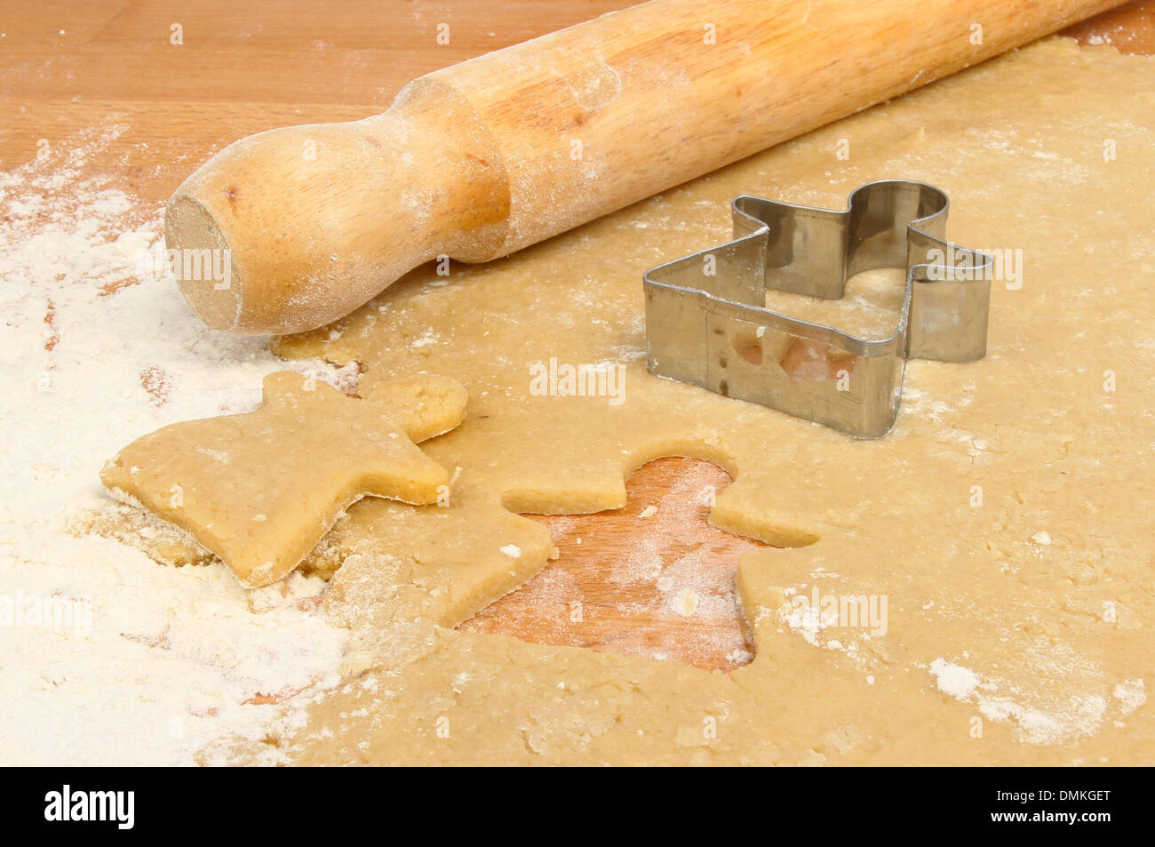 Rolling and cutting sweet pastry on a worktop with a rolling pin and angel cutter Stock Photo