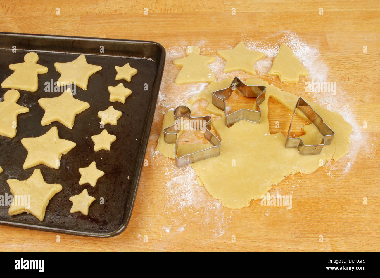 Cookie cutters and shortbread shapes on a board and a baking tray Stock Photo