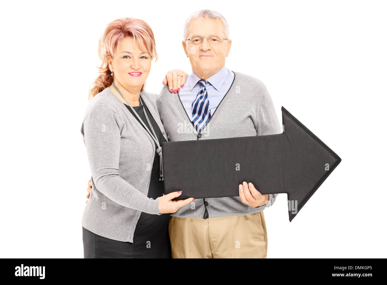 Smiling mature man and woman holding a big black arrow pointing right ...
