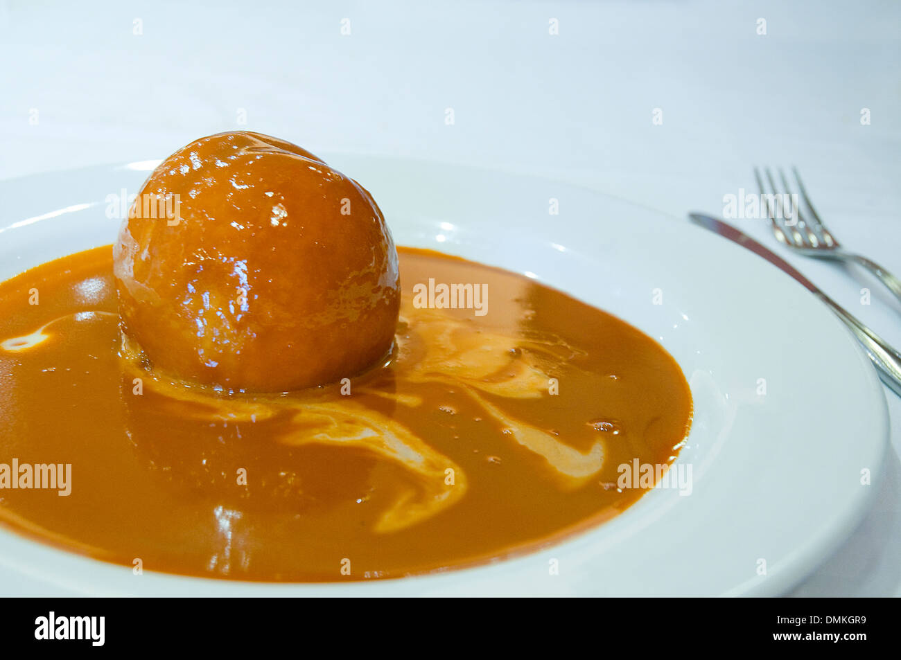 Dessert: Baked peach with toffee sauce. Close view. Stock Photo
