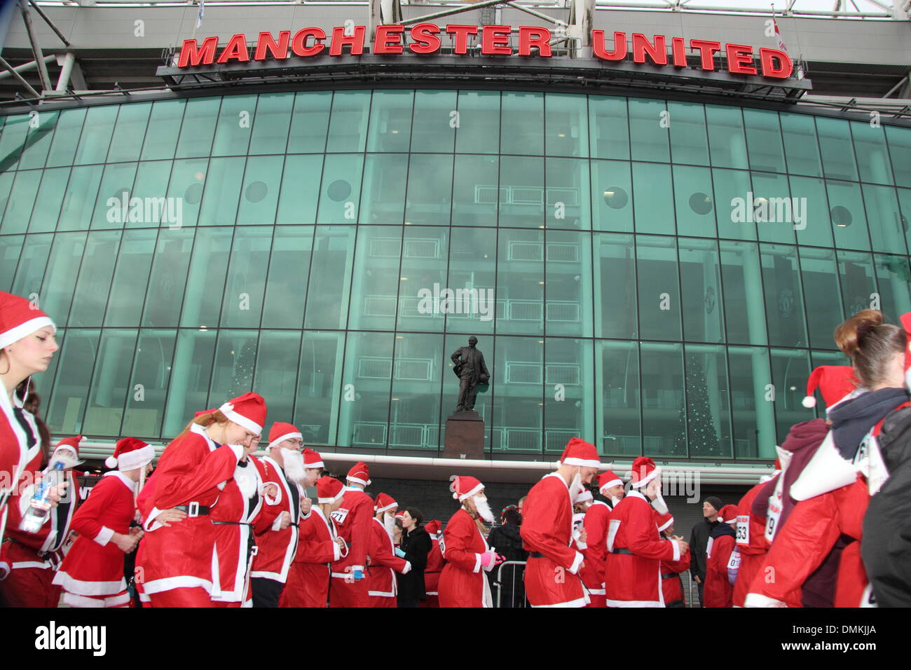 Old Trafford, Manchester, UK. 15th Dec 2013. Runners pass the Theatre of Dreams at the seventh annual Manchester United Foundation Santa Run. The Santa Run is a charity event with participants raising money for the Foundation and its charity partners Francis House Children’s Hospice, The Christie and UNICEF, or another charity of a participant’s choice. A Manchester United Foundation spokeswoman said more than 1500 runners participated. Credit:  Deborah Vernon/Alamy Live News Stock Photo