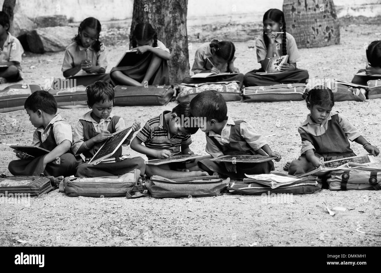 Rural Indian village school children in an outside class writing on a chalk tablets. Andhra Pradesh, India. Black and White. Stock Photo