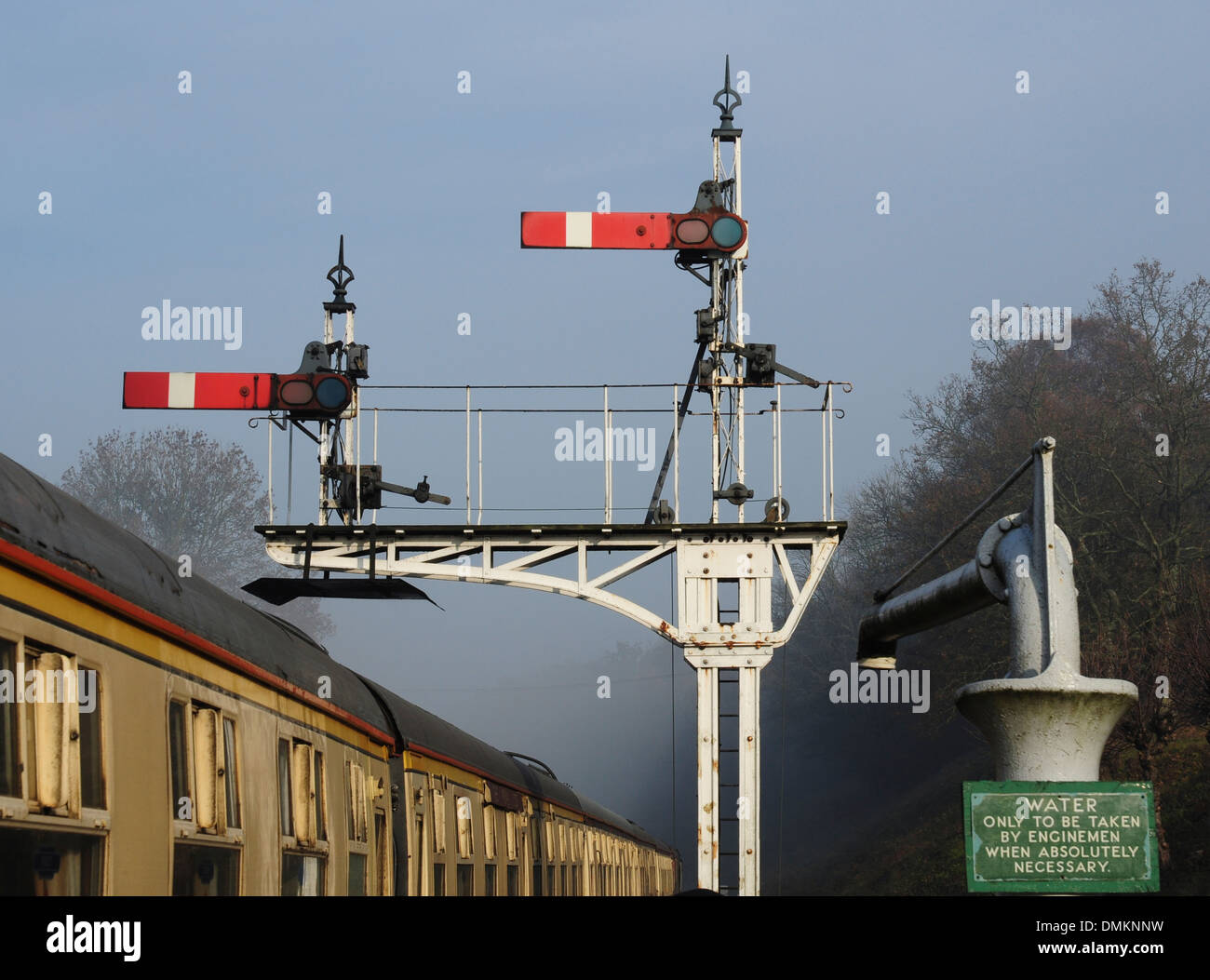 Semaphore signals and water crane in winter mist at Horsted Keynes station on the Bluebell Railway, Sussex, England, UK Stock Photo