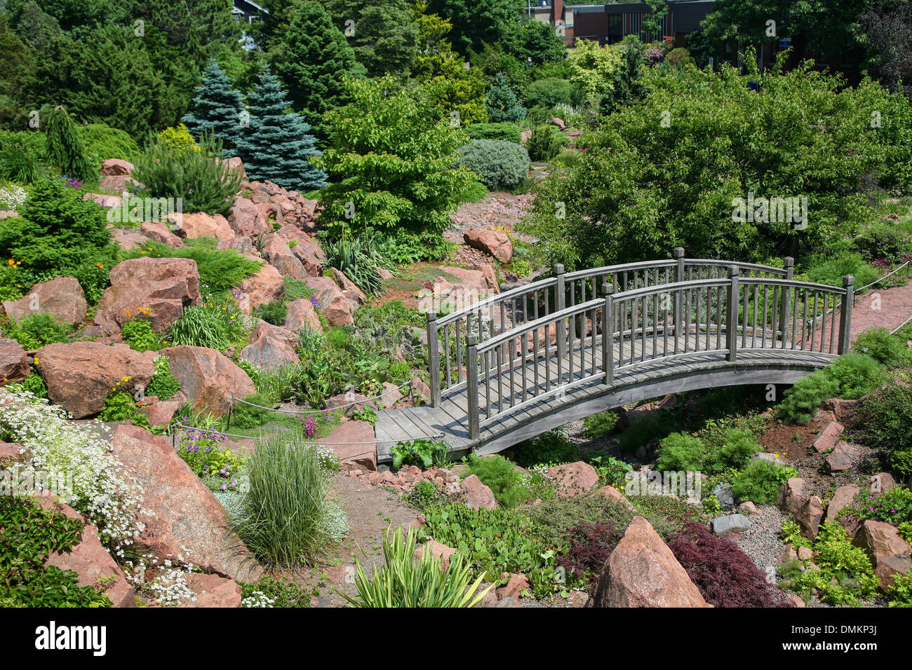 Wooden garden bridge in a alpine rock garden. Stock Photo