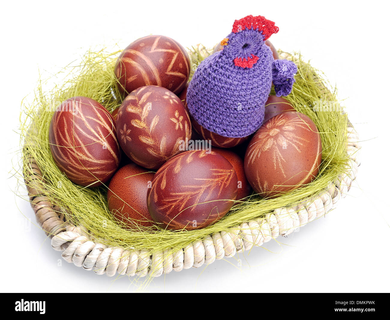 Crochet sitter sitting on easter eggs in wicker basket shot on white Stock Photo
