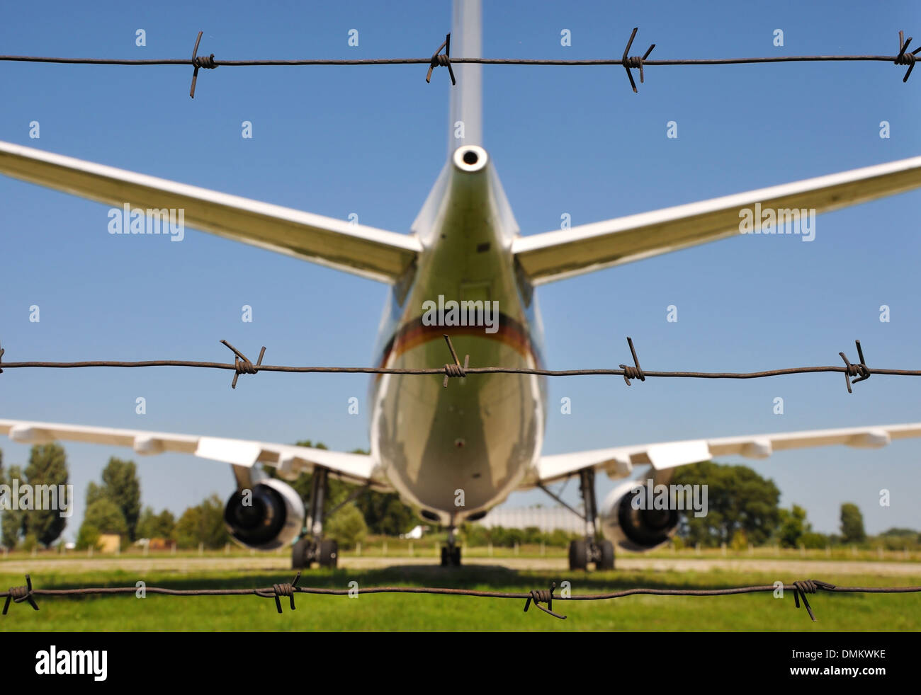 airplane behind three lines of barbwire Stock Photo