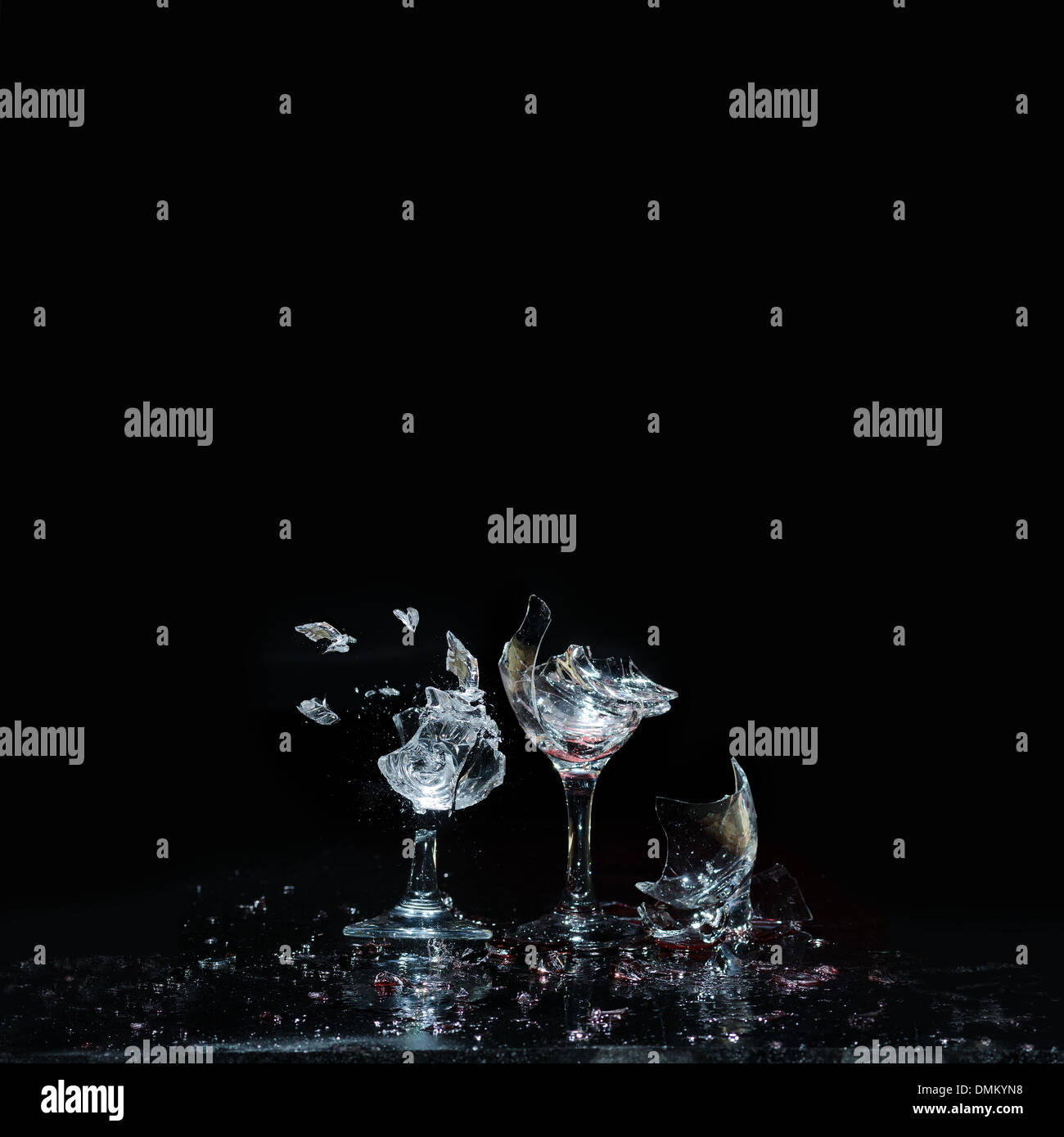 Smashing wine glasses on a reflective dark black background broken