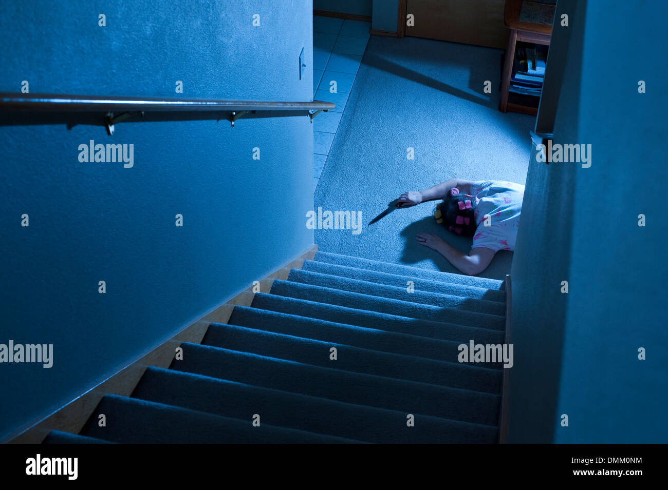 Woman lying at the bottom of stairs murder mystery clutching knife