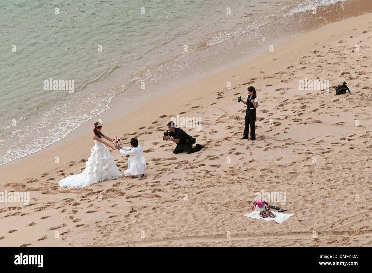 Newly-weds having destination wedding photos taken on Kaimana Beach (also known as Sans Souci Beach), Honolulu, Hawaii. Stock Photo