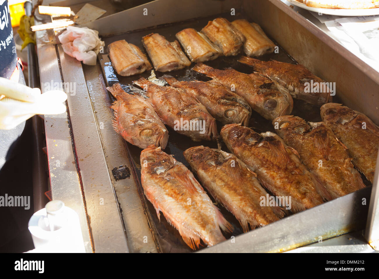 Whole fish frying on griddle at Jagalchi shijang (traditional outdoor market) - Busan, South Korea Stock Photo