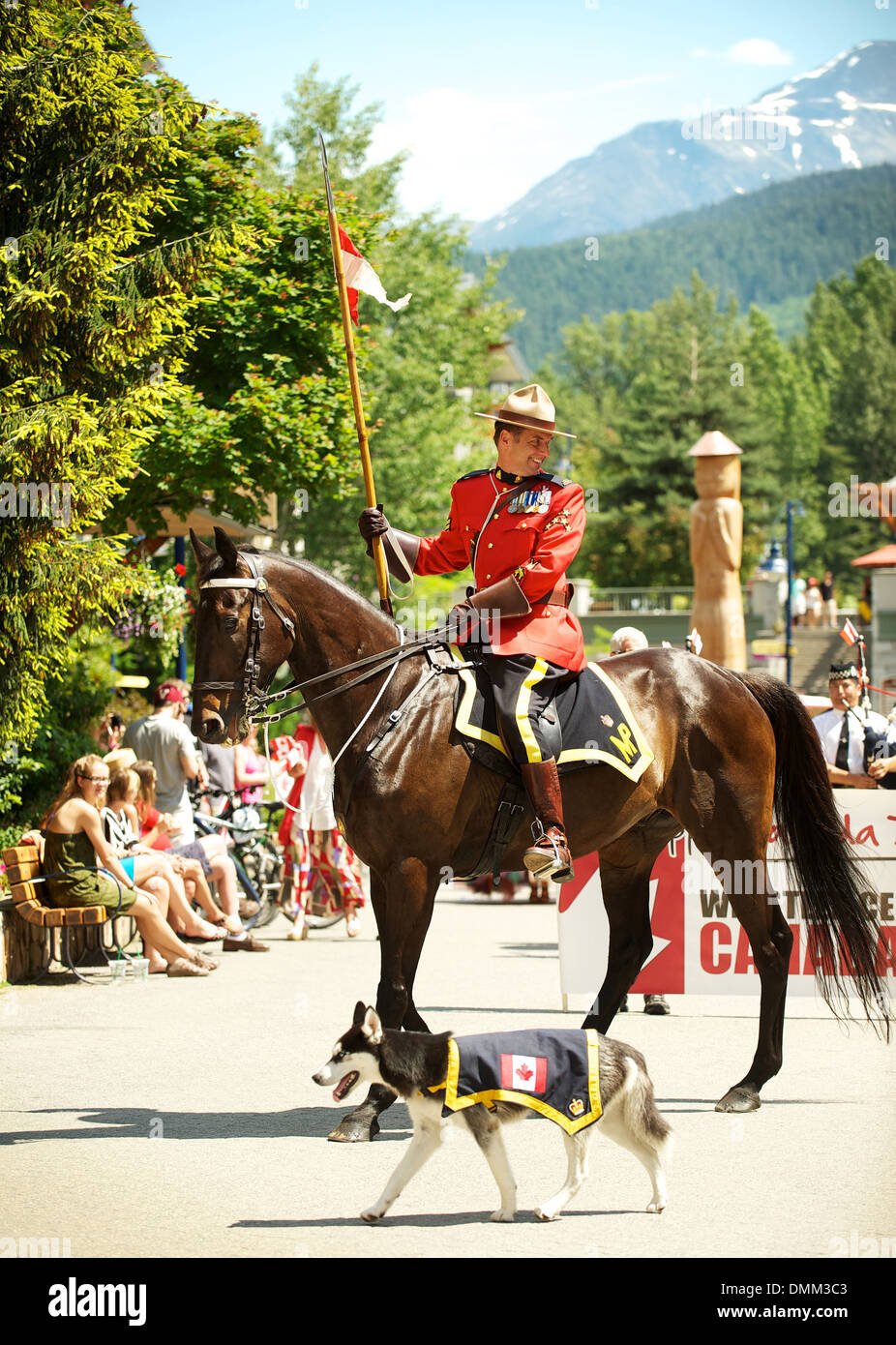 Royal Canadian Mounted Police officer mounted on a horse, wearing a formal red serge uniform parade through Whistler BC, Canada Stock Photo