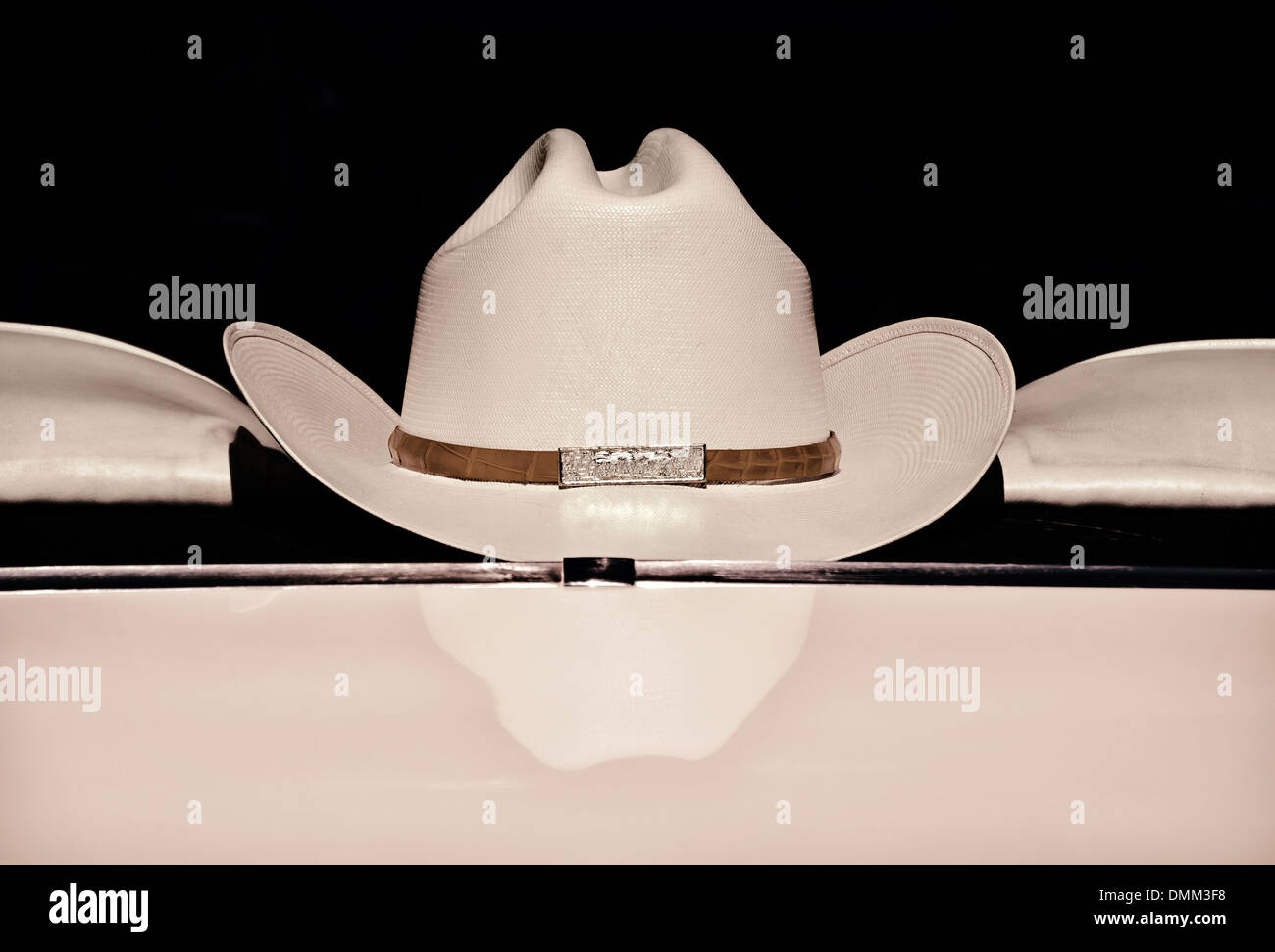 Cowboy hat displayed on the back of a car window against dark background, sepia color Stock Photo