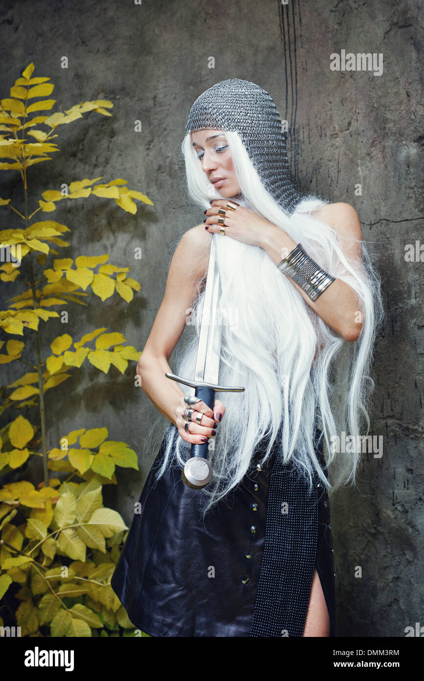 Attractive gray-haired maiden warrior in armor with sword in hand Stock Photo