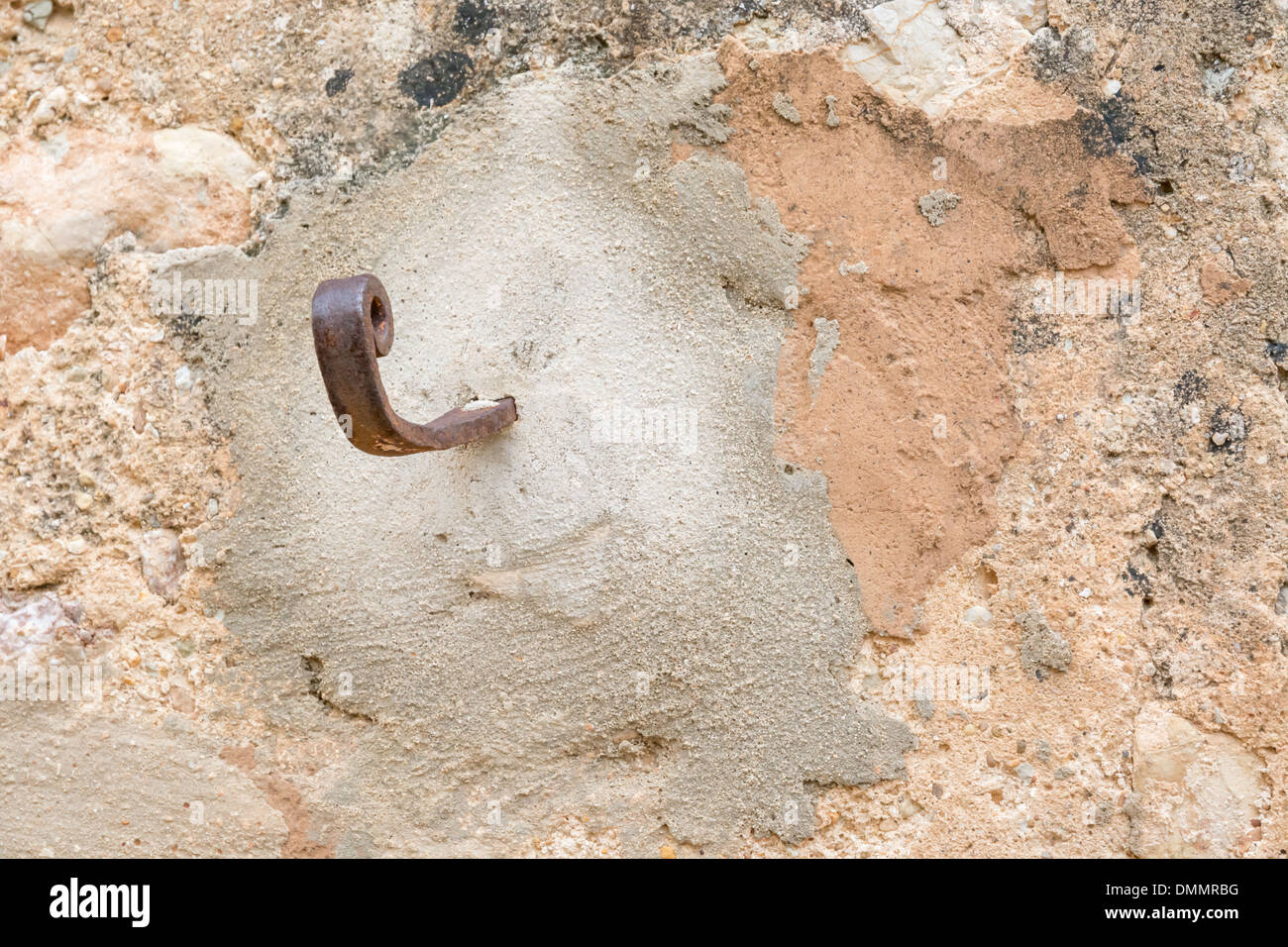 Rusty hook to the right on plastered wall with grungy look and warm ...