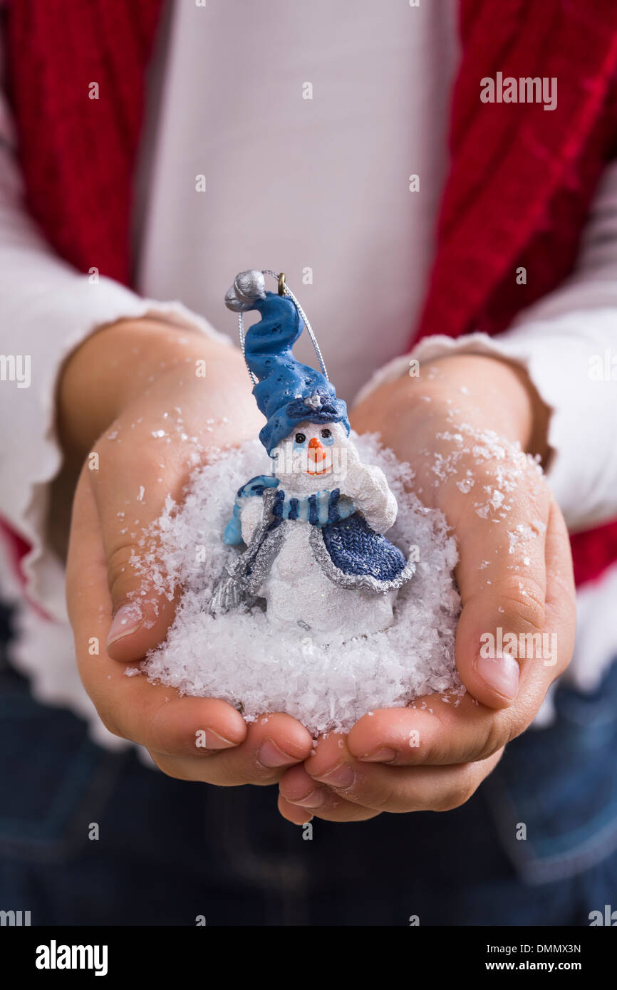 Hands of little girl holding snow and toy snowman Stock Photo
