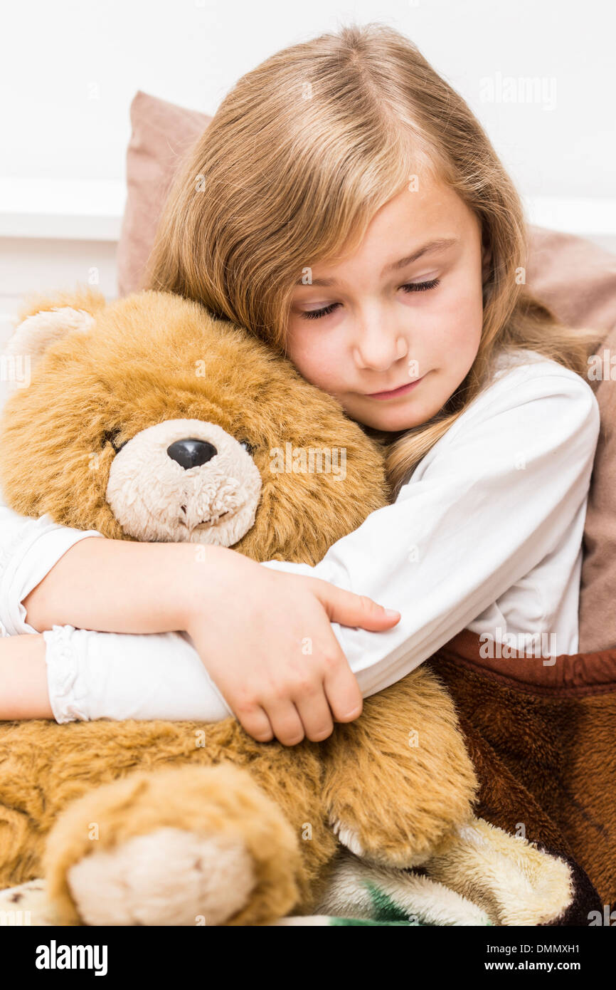 girl cuddling teddy bear