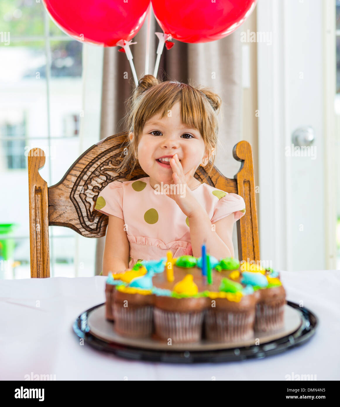 Happy Girl Sitting In Front Of Birthday Cake Stock Photo
