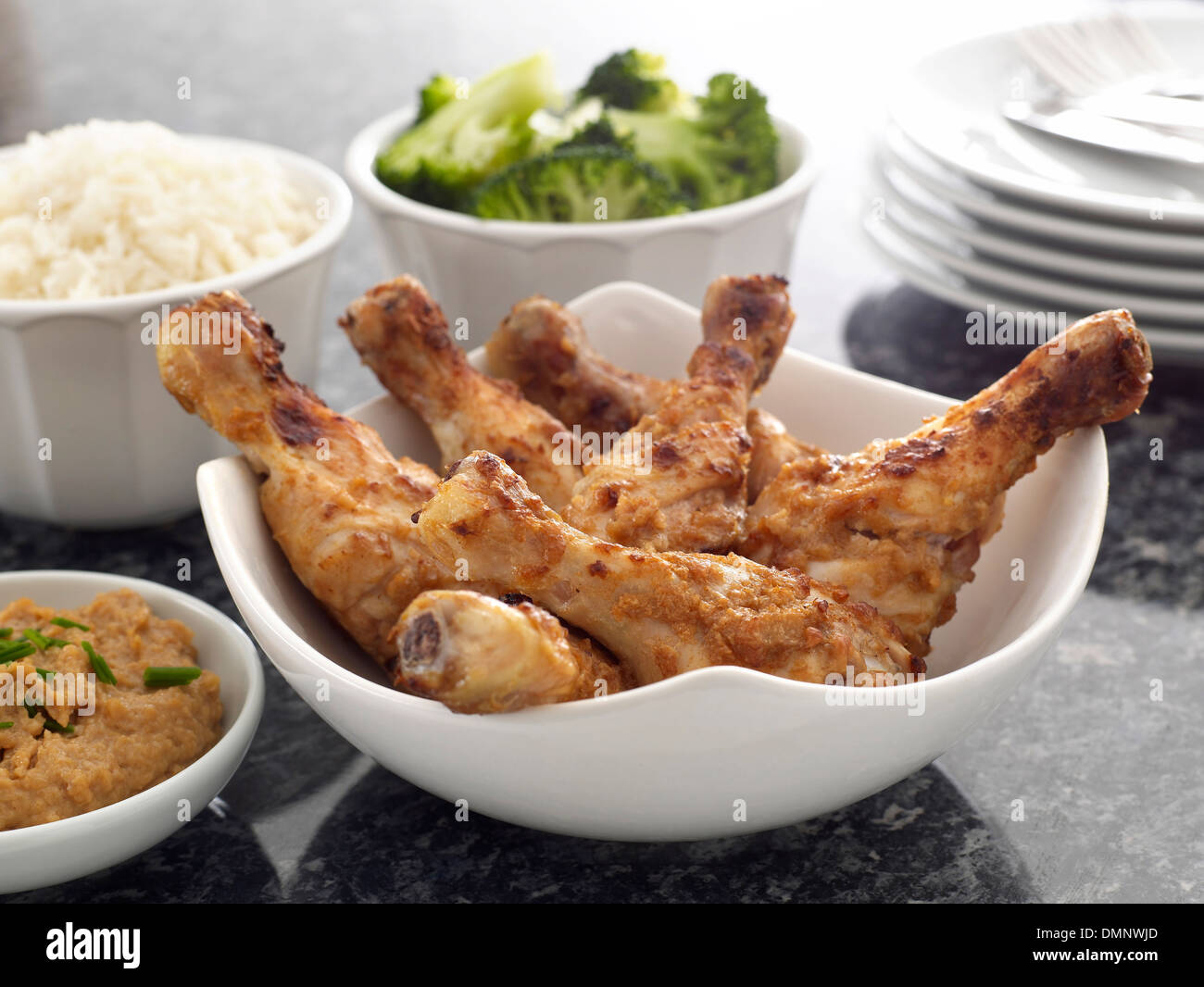 cooked chicken drumsticks pieces dip rice broccoli plates cutlery Stock