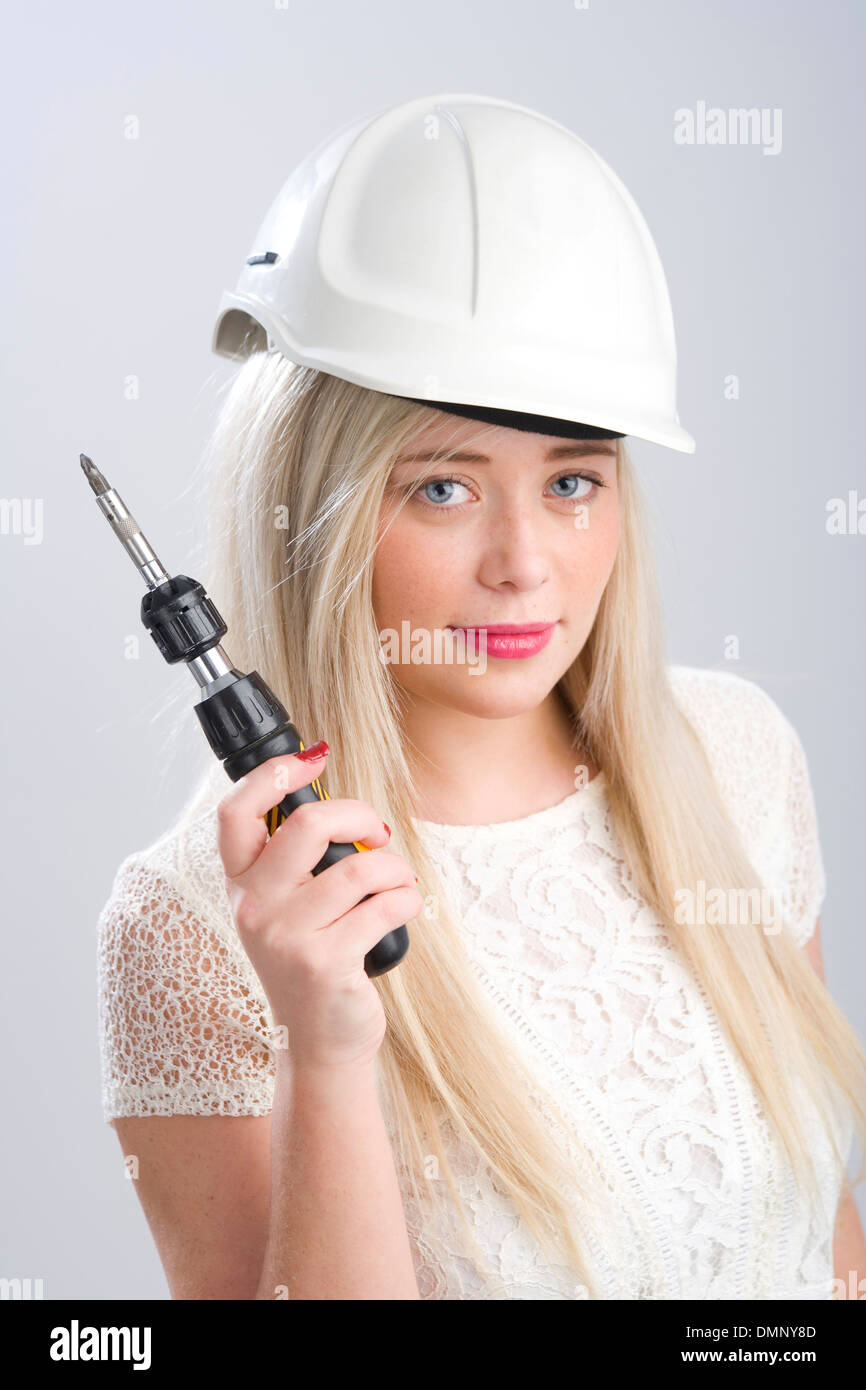 Pretty blonde woman wearing a hardhat and holding a screwdriver. Stock Photo