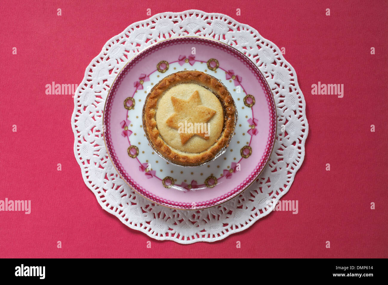 close up of mince pie with star on, on pink decorative plate and doilie ready for Christmas Stock Photo