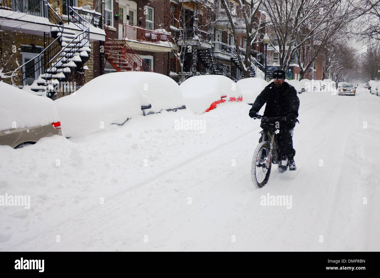 A man driving his electric bicycle down a snow covered road in Montreal, Quebec Stock Photo