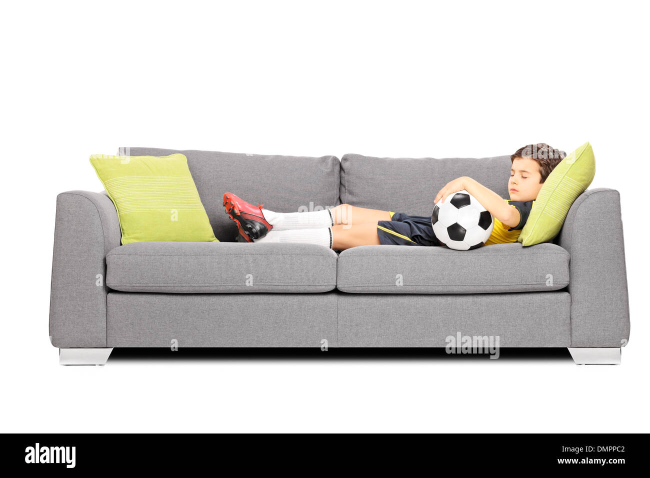 Boy in sportswear with a soccer ball sleeping on a modern sofa Stock Photo